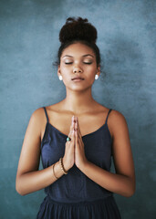 Poster - Finding inner peace. Cropped shot of a young woman meditating against a grey background.