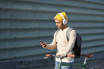 Wall Mural - Hispanic hipster chatting on phone and holding bicycle.