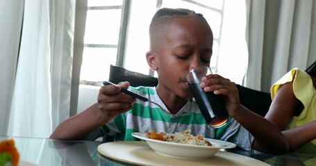 Wall Mural - Child eating lunch. Black African mixed race kid eats meal with family