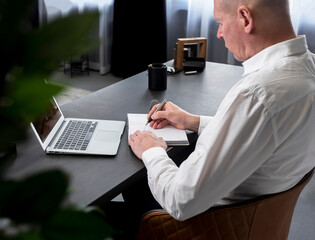 Poster - Businessman back at table with laptop and planner, note book. High quality photo