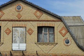 Poster - one big brown brick loft of a rural house with a window and a door on a background of blue sky 