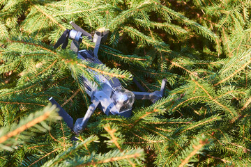Drone quadcopter accident scene. UAV Quadrocopter crashed on tree in forest. Drone quadcopter accident scene. Destroyed expensive drone hanging in the branches of spruce