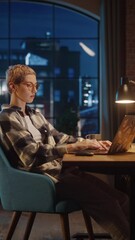 Aufkleber - Vertical Screen: Young Attractive Woman Using Laptop Computer in Stylish Loft Apartment in the Evening. Creative Female Checking Social Media, Browsing Internet, Wearing Cozy Clothes.