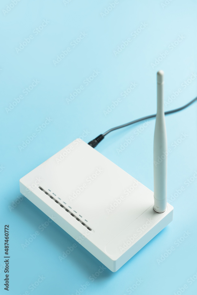 Wi-Fi router with antenna and network cable on color background