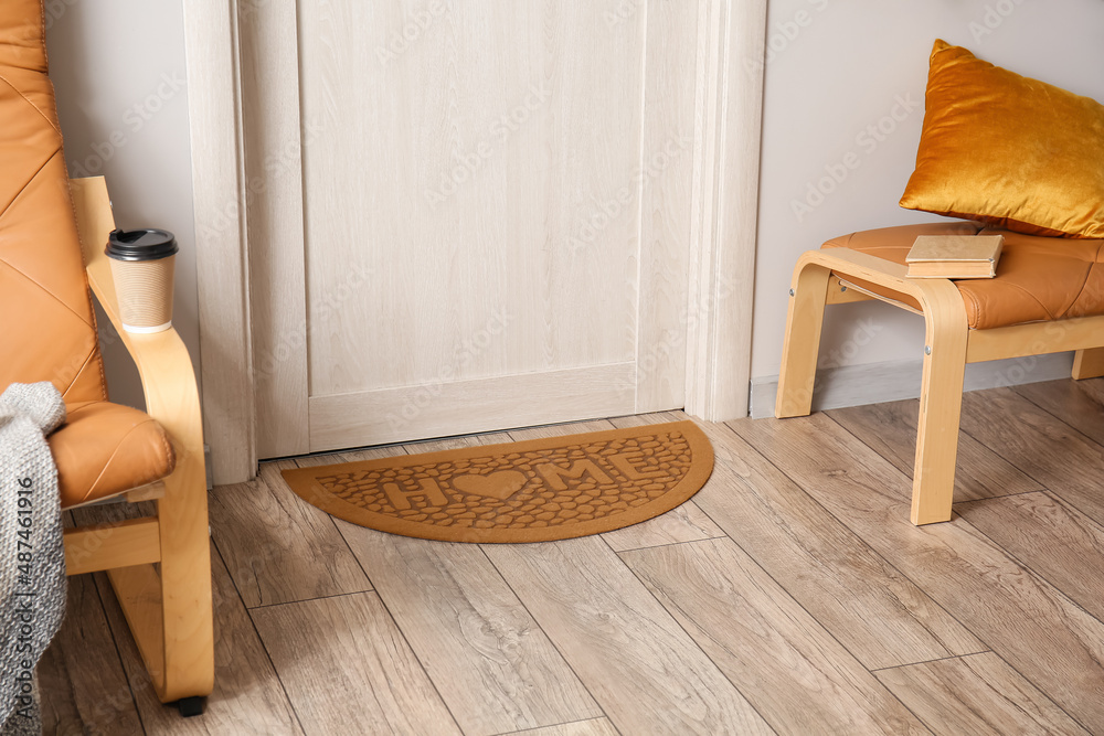 Stylish mat near light wooden door in hall