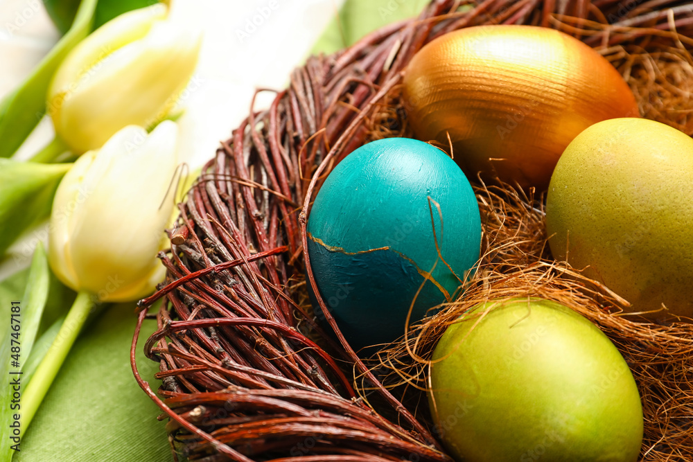 Nest with painted Easter eggs and tulips on light background