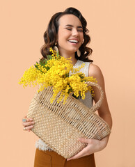 Wall Mural - Beautiful young woman with mimosa flowers in bag on color background