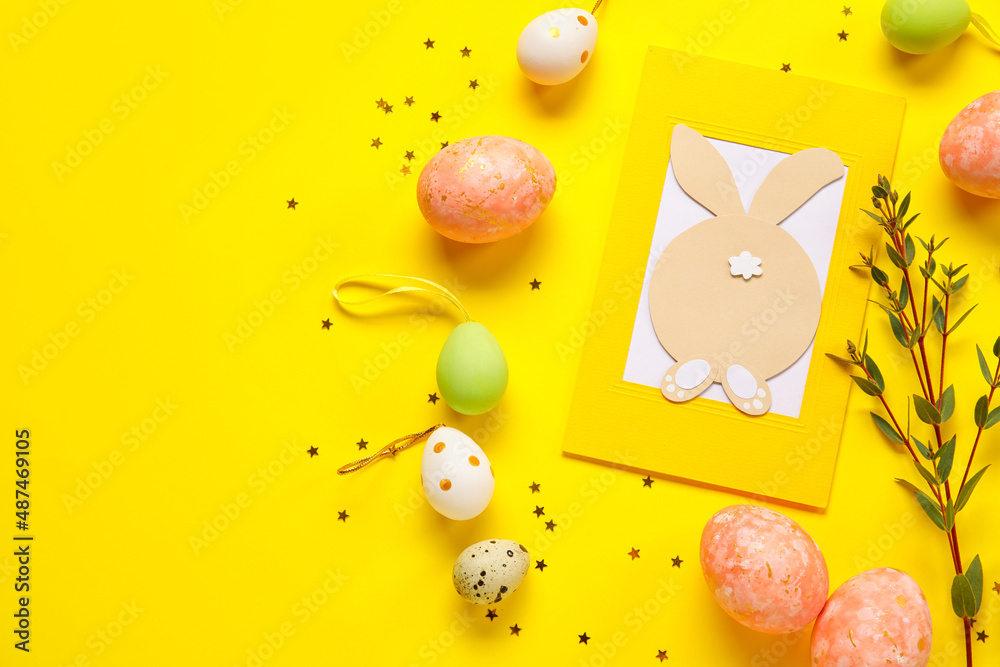 Beautiful Easter composition with greeting card and painted eggs on yellow background