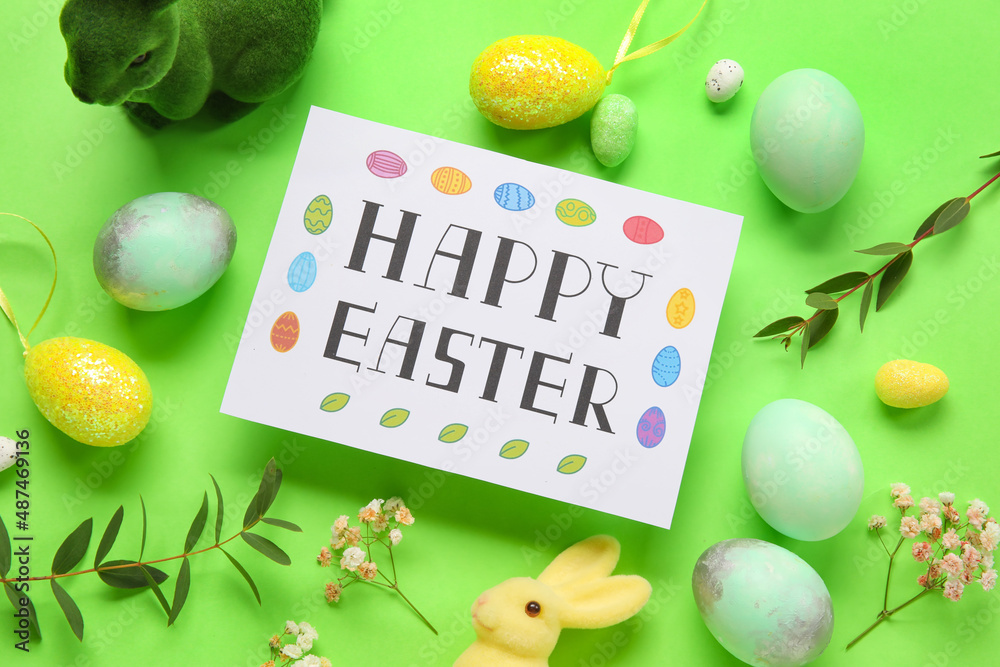 Beautiful Easter composition with greeting card, painted eggs, bunnies and flowers on green background
