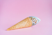 A Hundred Dollars In An Ice Cream Cone. Unusual Ice Cream With A Bill. A Horn With Money On A Pink Background. Interesting And Abstract Subject Shooting