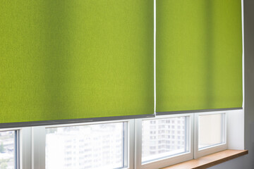 Wall Mural - Roller blinds closeup on the window in the interior. Roller shades for big windows. Electric curtains for office. Green color, monochrome material. Window coverings.