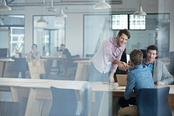 Wall Mural - Welcome to the team. Through the glass shot of a group of colleagues working together in an office.