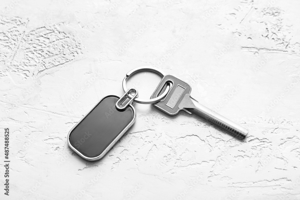 Key with stylish steel keychain on light background