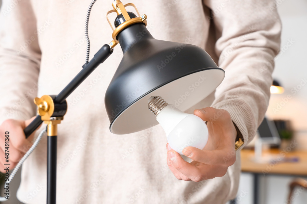 Man changing light bulb in office lamp, closeup