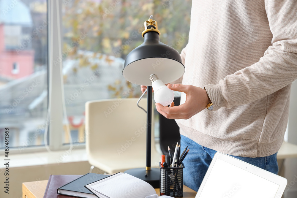 Man changing light bulb in office lamp