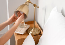 Woman Changing Light Bulb In Golden Lamp At Home, Closeup