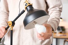 Man Changing Light Bulb In Office Lamp, Closeup