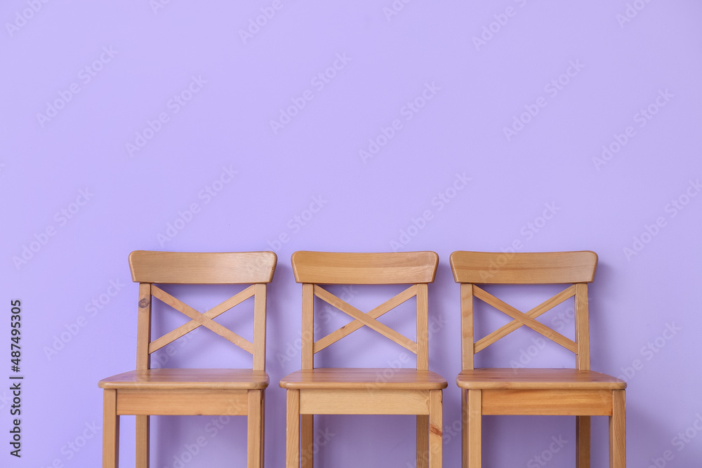 Wooden chairs near violet wall