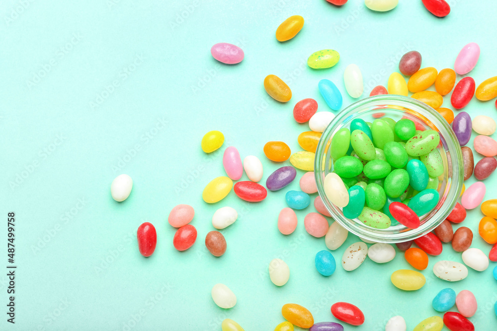 Bowl with different jelly beans on color background