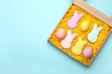 Canvas Print - Box with delicious Easter cookies in shape of bunny and painted eggs on blue background