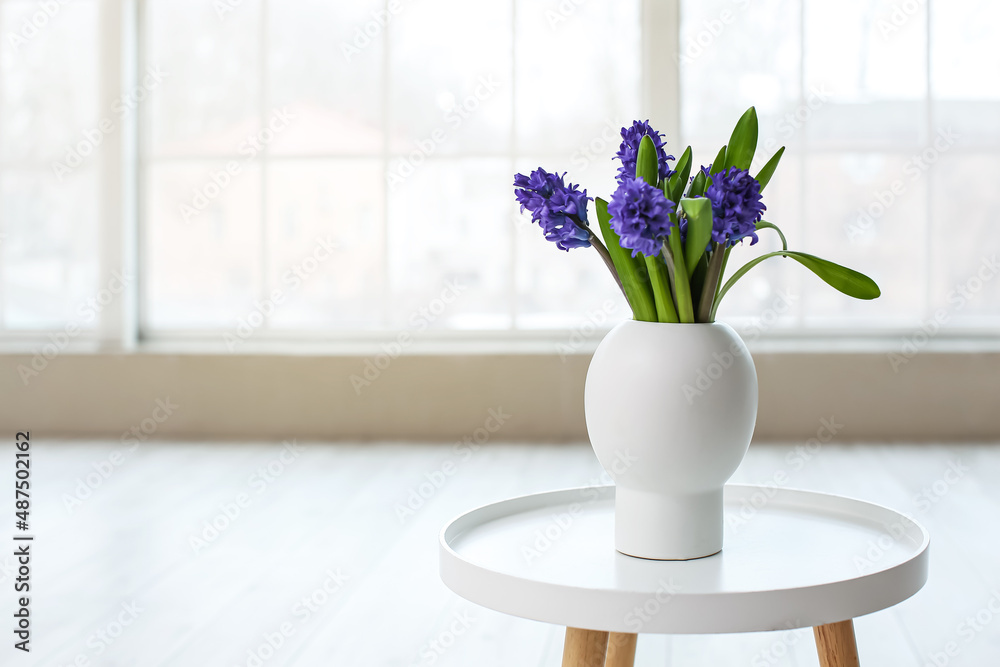 Vase with beautiful flowers on table in light room