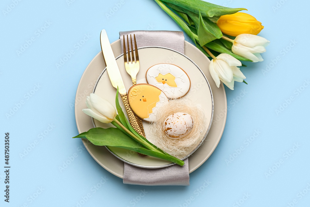 Stylish table setting with Easter cookies on blue background