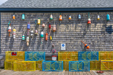 The Gray Plank Wall Of A Traditional Home Is Adorned With Old Floats And Lobster Traps As A Symbol Of A New England Fishing Village By The Atlantic Ocean.