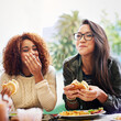 © Marius Venter/peopleimages.com - Sharing good food and great jokes. Cropped shot of two girlfriends eating burgers outdoors.