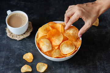 Wall Mural - spicy masala tapioca chips Keripik singkong or Cassava chips Indian milk tea chai India Indonesia Brazil Sri Lanka woman hand serving Kerala fried snacks food tea time food fried in coconut oil