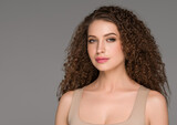 Fototapeta  - Curly long brunette hair woman beauty portrait, female glamour face. Color backgound gray