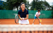 © NDABCREATIVITY - Tennis sport people concept. Mixed doubles player hitting tennis ball with partner standing near net