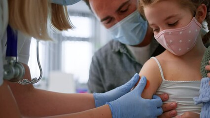 Wall Mural - little girl sitting on fahter's lap and getting vaccinated in doctor's office