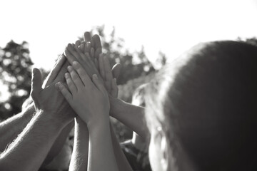 Wall Mural - Group of volunteers joining hands together outdoors. Black and white effect