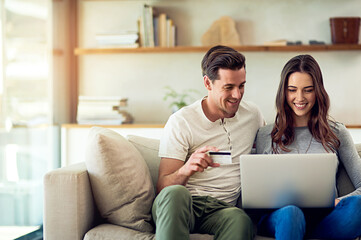 Wall Mural - Lets treat ourselves. Weve earned it. Shot of a happy young couple making a credit card payment on a laptop together at home.