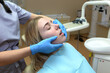 © Tania - European young woman sits in a medical chair while a dentist examines her teeth in a dental clinic.
