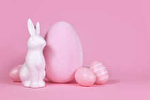 White Bunny Sculpture With Easter Eggs On Pink Background With Copy Space