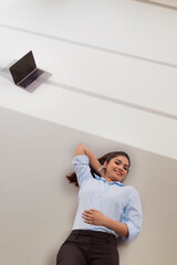 Wall Mural - Young business woman in formal outfit lying on floor with hand behind neck