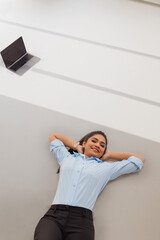 Wall Mural - Young business woman in formal outfit lying on floor with hands behind neck