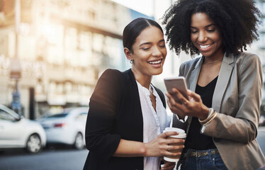 Aufkleber - Good news just came in from the office for us. Shot of two businesswomen looking at something on a cellphone in the city.