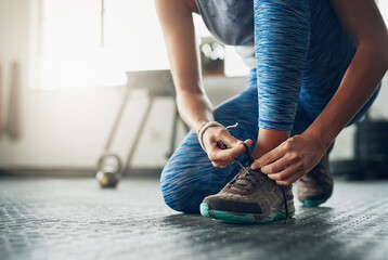 Poster - the right shoes makes all the difference. shot of a woman tying her shoelaces in a gym.