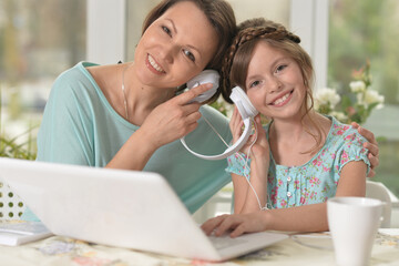 mother and daughter  with headphones using laptop