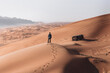 Man walking in huge red desert dunes