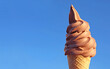 © jobi_pro - Chocolate Soft Serve Ice Cream Cone Against Vibrant Blue Sunny Sky
