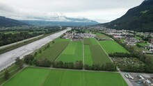 Aerial View Of Liechtenstein With Houses On Green Fields Among A Mountain Valley In The Alps. Scenic Panorama Of Vaduz Valley By The River Rhine. Drone View Of Hillside Villages An Alpine Country. 4K