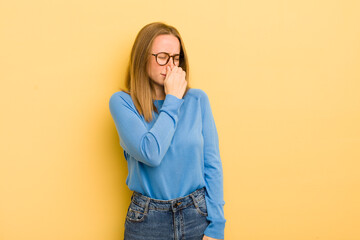 Wall Mural - pretty caucasian woman feeling disgusted, holding nose to avoid smelling a foul and unpleasant stench