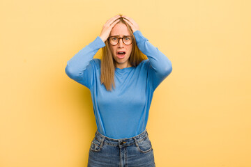 Wall Mural - pretty caucasian woman feeling horrified and shocked, raising hands to head and panicking at a mistake