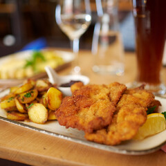 Wall Mural - Saftiger Wiener Schnitzel vom Kalb mit wellen Panade und Bratkartoffeln auf schönem Teller 