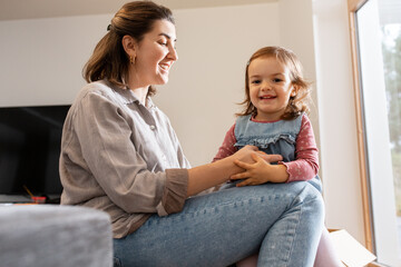 Sticker - family, hygge and people concept - happy mother and little daughter playing at home