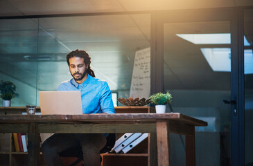 Fototapete - Working late but working hard. Cropped shot of a young designer working late on a laptop in an office.