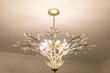 warm gold lighting fixture chandelier with fanned out leaves against a white wall